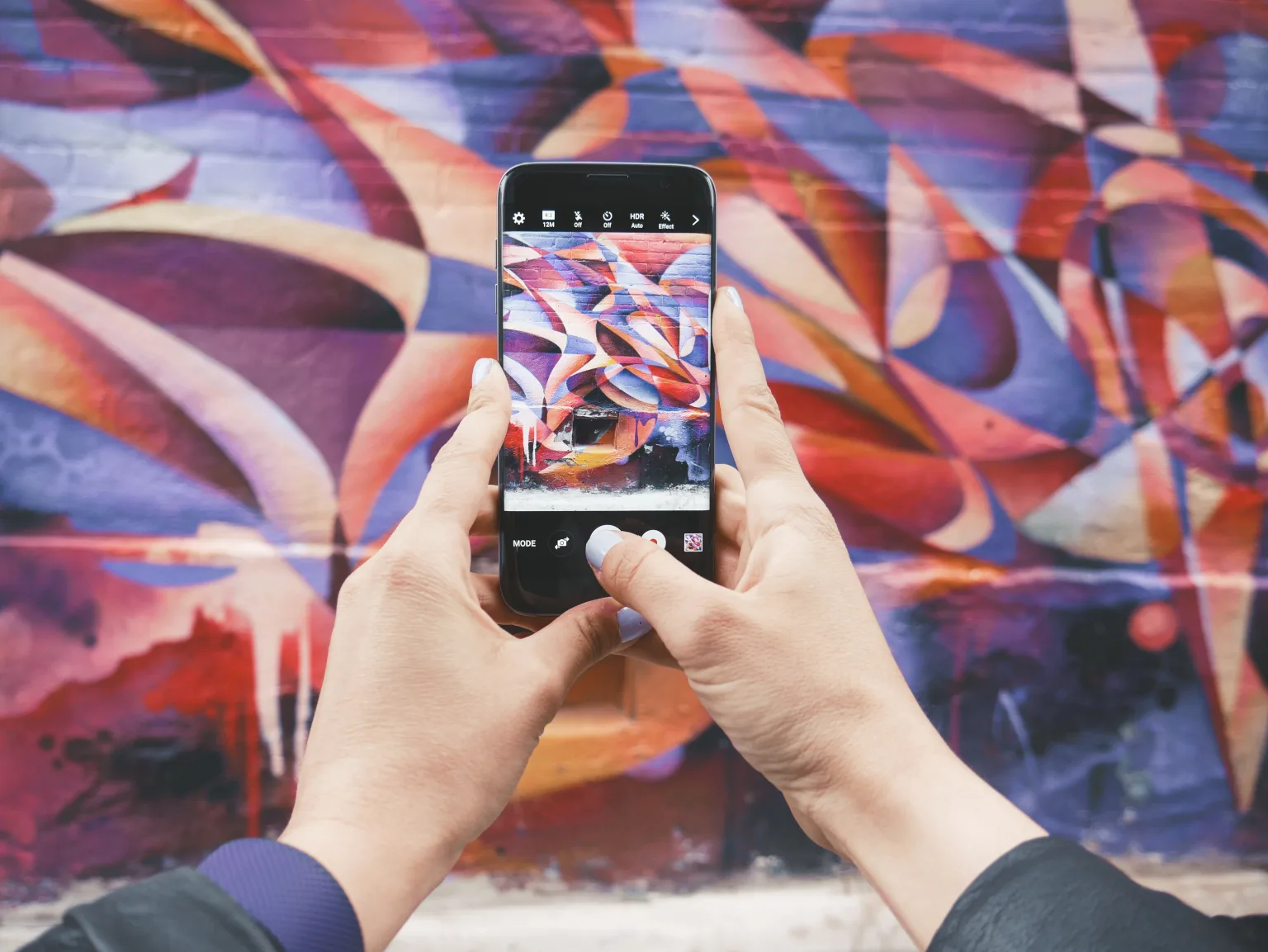 A person taking a picture of a colorful wall.